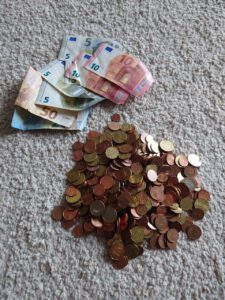Geldscheine und Münzen liegen auf einem Teppich